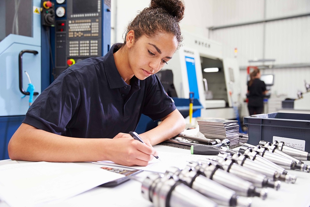 Engineer Planning Project With CNC Machinery In Background