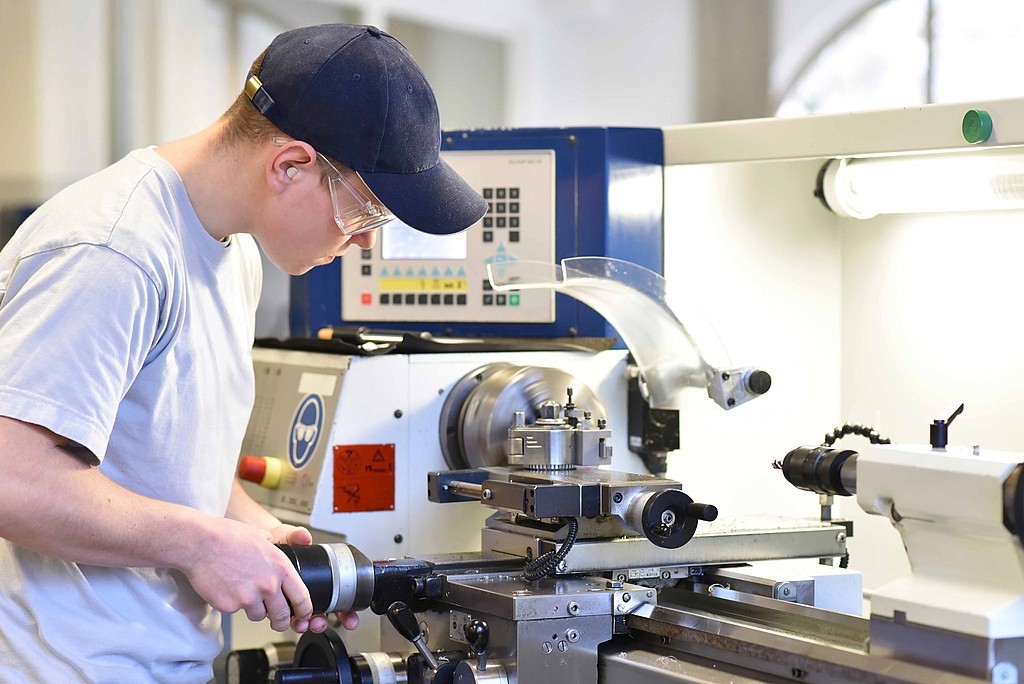 young apprentice in vocational training working on a turning machine in the industry